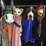 Handpuppen, ein Esel, Katze, Hund und Huhn hängen baumelnd an einer Kleiderstange. Zu dem Stück die Bremer Stadtmusikanten.